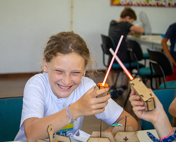 Criança a sorrir enquanto explora um projeto com luz