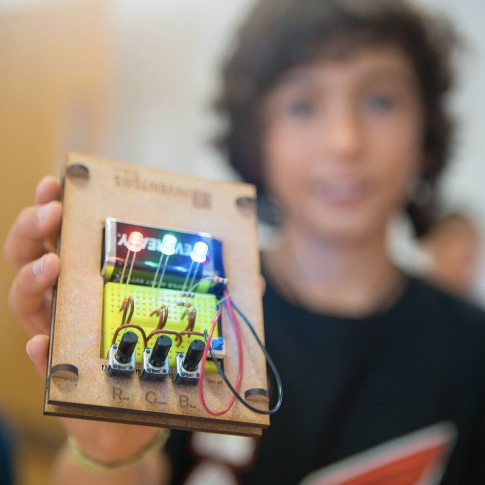 Criança a mostrar com orgulho a sua invenção eletrónica